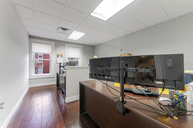 office area with baseboards, visible vents, hardwood / wood-style flooring, and a drop ceiling