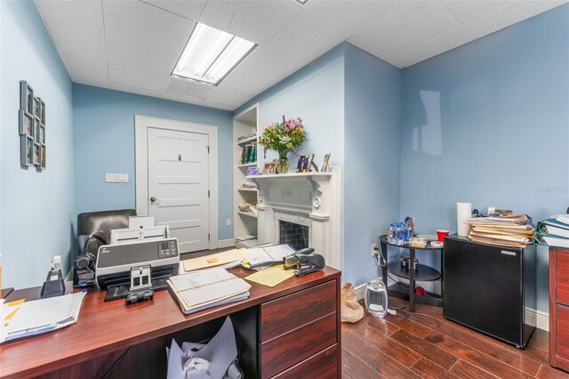 office space featuring baseboards, dark wood-style flooring, and a paneled ceiling
