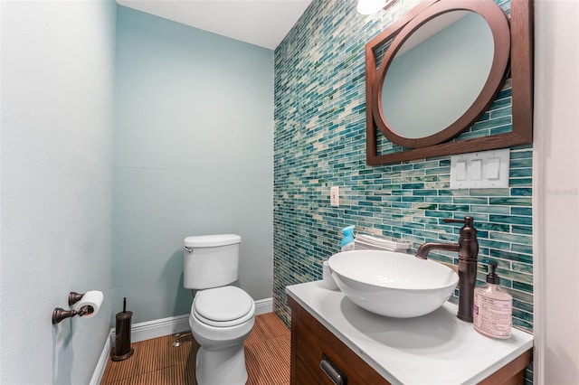 half bath featuring wood finished floors, tile walls, toilet, vanity, and baseboards