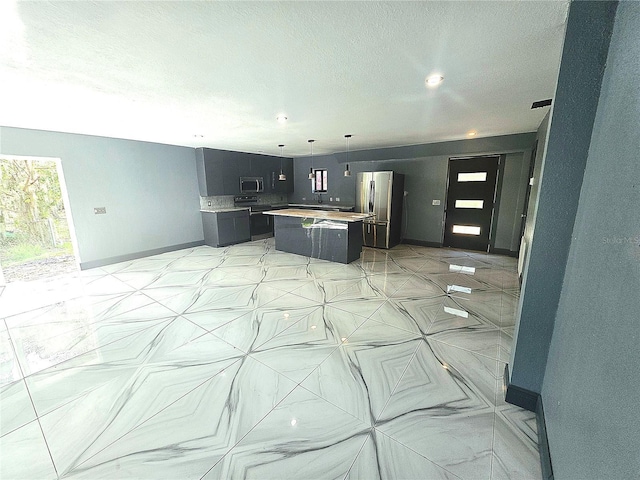 3911 6th Ave W, Palmetto, FL 34221 - kitchen featuring stainless steel appliances, a center island, light countertops, a textured ceiling, and decorative light fixtures