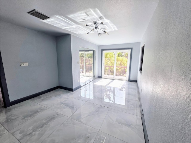 3911 6th Ave W, Palmetto, FL 34221 - empty room with a chandelier, a textured wall, light marble finish floors, and a textured ceiling