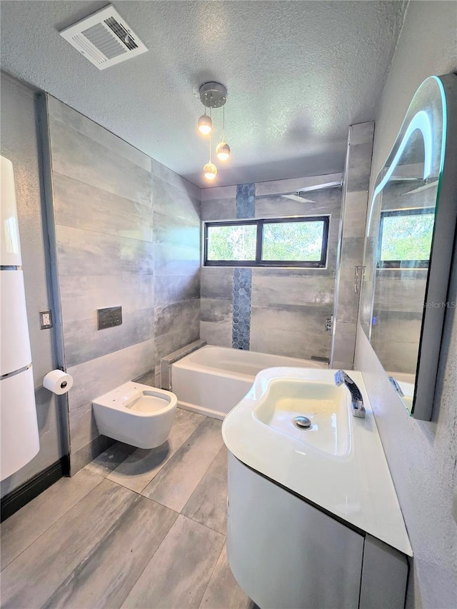 3911 6th Ave W, Palmetto, FL 34221 - full bath with a bidet, vanity, a textured ceiling, a bathtub, and tile walls
