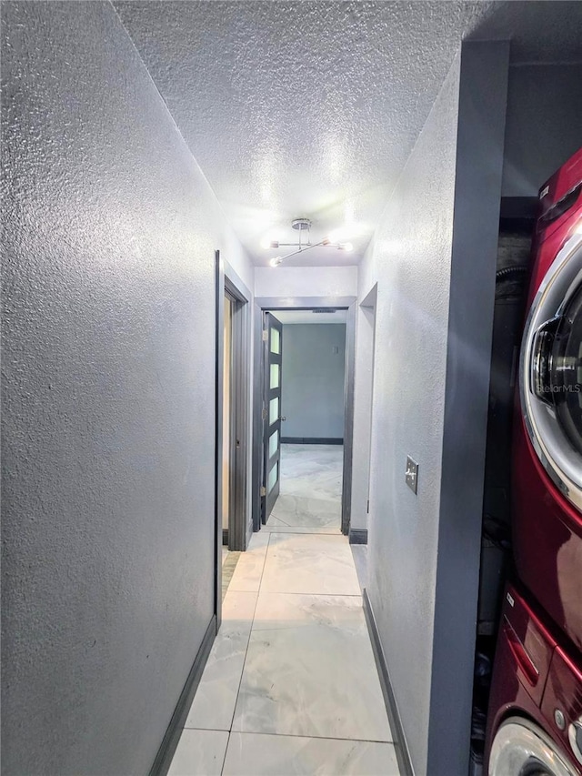3911 6th Ave W, Palmetto, FL 34221 - hallway with estacked washer and dryer, light marble finish floors, a textured wall, and a textured ceiling
