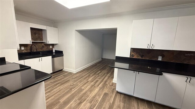 7017 Baywood Dr, Tampa, FL 33637 - kitchen with stainless steel dishwasher, ornamental molding, a sink, white cabinets, and tasteful backsplash