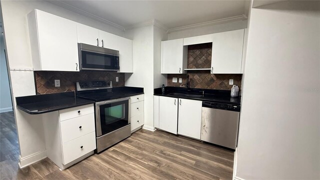 7017 Baywood Dr, Tampa, FL 33637 - kitchen with dark countertops, appliances with stainless steel finishes, wood finished floors, and ornamental molding