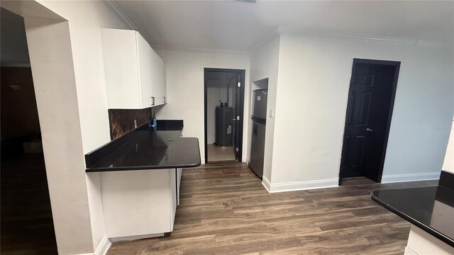 7017 Baywood Dr, Tampa, FL 33637 - kitchen featuring dark countertops, crown molding, dark wood-type flooring, and white cabinets