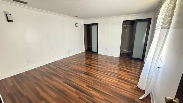7017 Baywood Dr, Tampa, FL 33637 - unfurnished bedroom featuring baseboards, visible vents, crown molding, wood finished floors, and multiple closets
