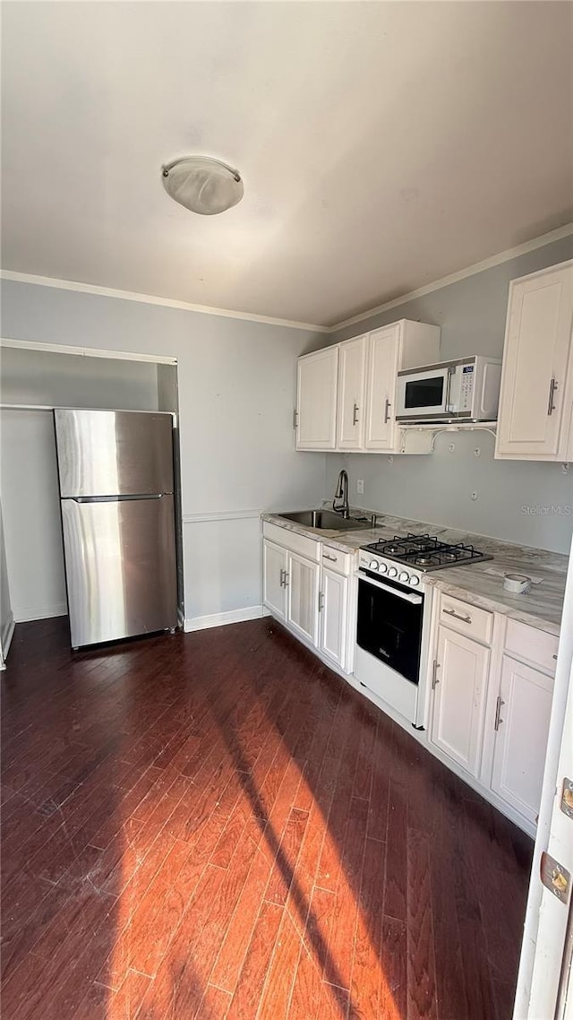 7017 Baywood Dr, Tampa, FL 33637 - kitchen with a sink, white appliances, dark wood-style flooring, white cabinets, and baseboards