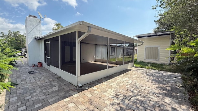 7017 Baywood Dr, Tampa, FL 33637 - rear view of property featuring a chimney, a patio area, and a sunroom
