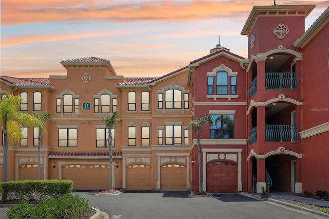 property at dusk featuring an attached garage and driveway