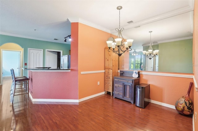 dining area featuring visible vents, wood finished floors, baseboards, a notable chandelier, and ornamental molding