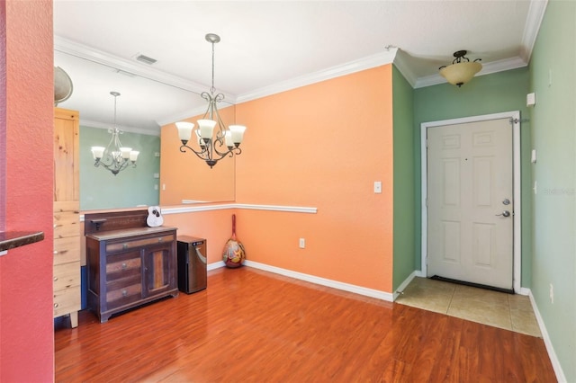 interior space with visible vents, wood finished floors, baseboards, a notable chandelier, and ornamental molding