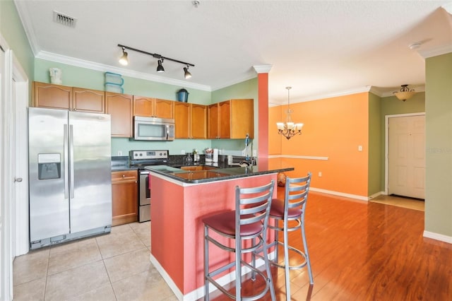 kitchen with stainless steel appliances, dark countertops, visible vents, and ornamental molding