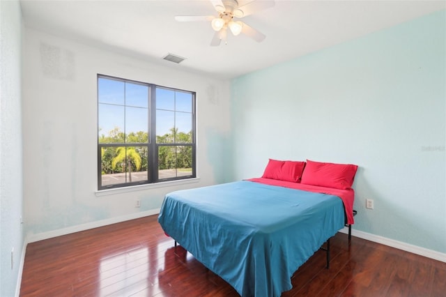 bedroom featuring ceiling fan, baseboards, visible vents, and wood finished floors
