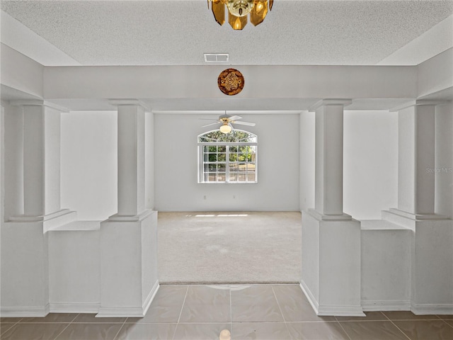 interior space with ornate columns, visible vents, ceiling fan, and a textured ceiling