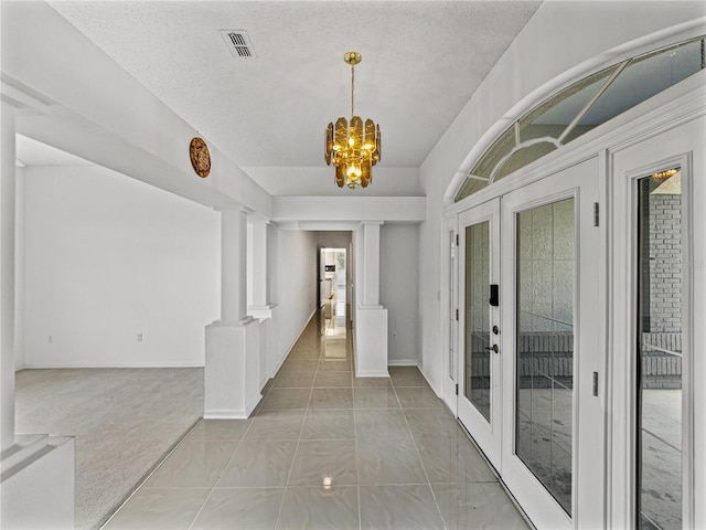 foyer featuring visible vents, decorative columns, an inviting chandelier, and french doors