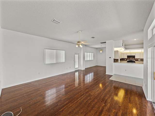 unfurnished living room with visible vents, wood finished floors, ceiling fan, and a textured ceiling