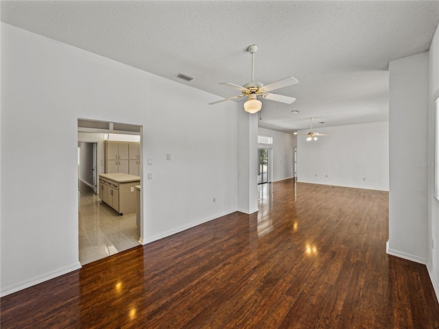 unfurnished living room featuring wood finished floors, ceiling fan, baseboards, visible vents, and a textured ceiling