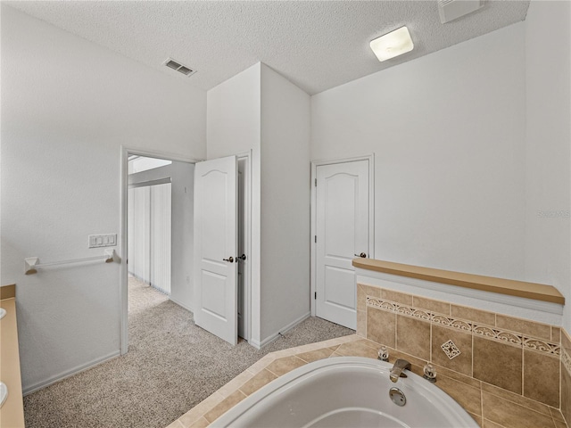 bathroom with a textured ceiling, visible vents, a bath, and baseboards