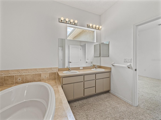 full bath featuring double vanity, a textured ceiling, a garden tub, and a sink