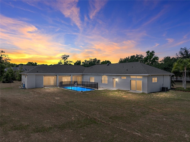 back of property featuring a lawn, stucco siding, cooling unit, and an outdoor pool