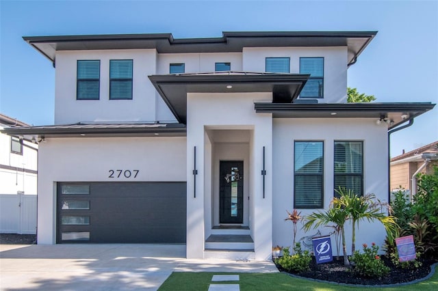 view of front of home featuring a standing seam roof, stucco siding, concrete driveway, an attached garage, and fence