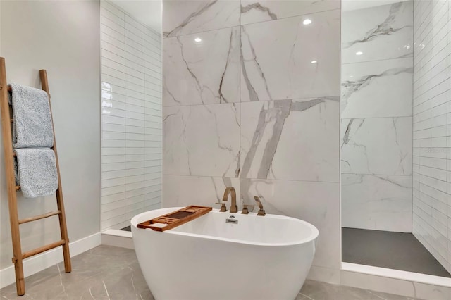 bathroom featuring a freestanding tub, a tile shower, marble finish floor, and tile walls