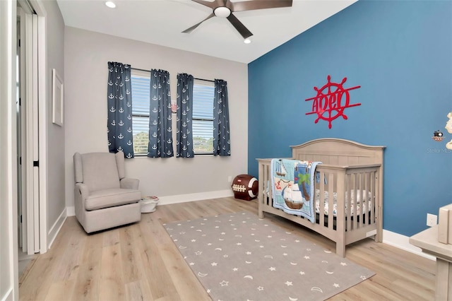 bedroom featuring wood finished floors, a nursery area, and baseboards