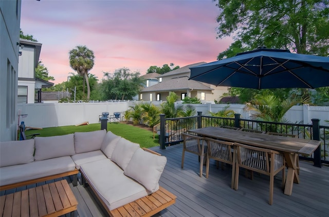 deck at dusk with an outdoor living space, outdoor dining area, a fenced backyard, and a yard