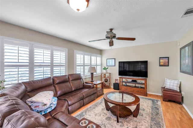 9335 Stonewall, New Port Richey, FL 34655 - living room featuring light wood-style flooring, ceiling fan, baseboards, and a textured ceiling