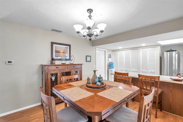 9335 Stonewall, New Port Richey, FL 34655 - dining area featuring a chandelier, light wood-style flooring, baseboards, and a textured ceiling