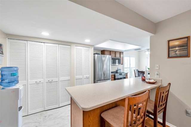 9335 Stonewall, New Port Richey, FL 34655 - kitchen with stainless steel appliances, a peninsula, light marble finish floors, a kitchen bar, and light countertops