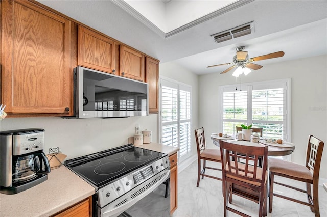 9335 Stonewall, New Port Richey, FL 34655 - kitchen with stainless steel appliances, ceiling fan, brown cabinetry, light countertops, and light marble finish floors