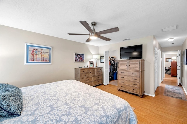 9335 Stonewall, New Port Richey, FL 34655 - bedroom featuring light wood-type flooring, a textured ceiling, ceiling fan, a closet, and a walk in closet