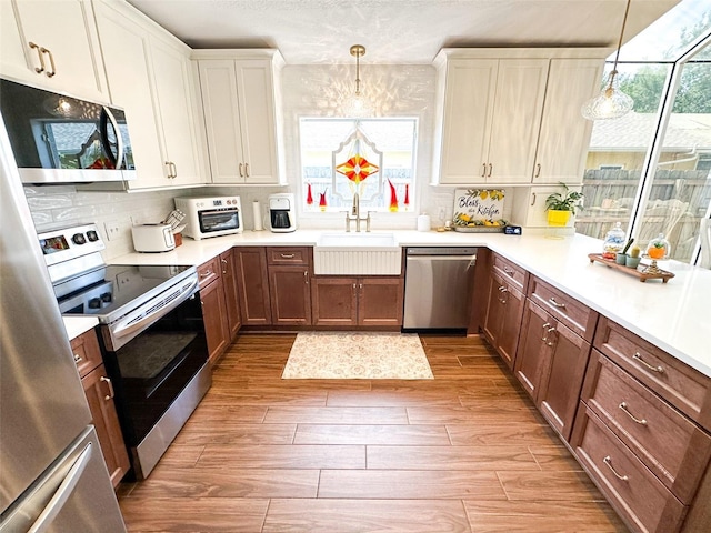 kitchen featuring a sink, range with electric cooktop, light wood-type flooring, tasteful backsplash, and stainless steel dishwasher
