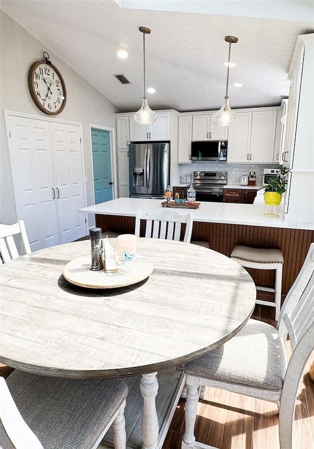 dining room featuring visible vents, lofted ceiling, and recessed lighting