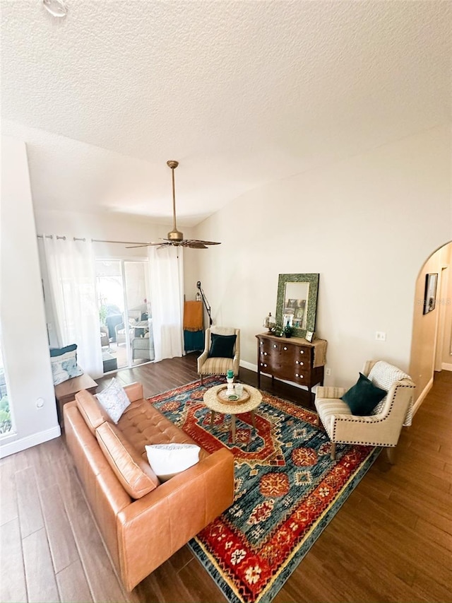 living area featuring wood finished floors, a healthy amount of sunlight, baseboards, and arched walkways