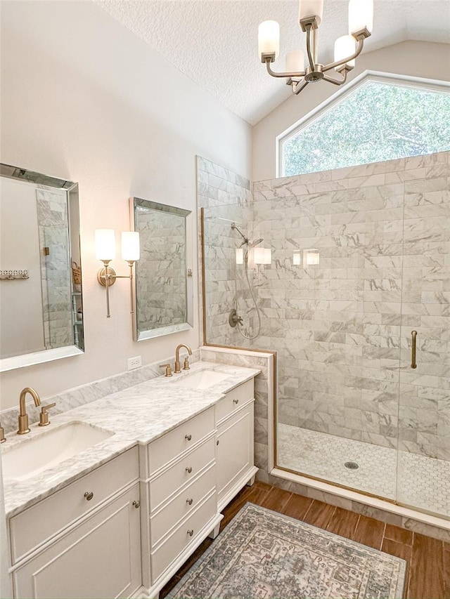 full bath featuring a stall shower, a notable chandelier, wood finished floors, and a sink