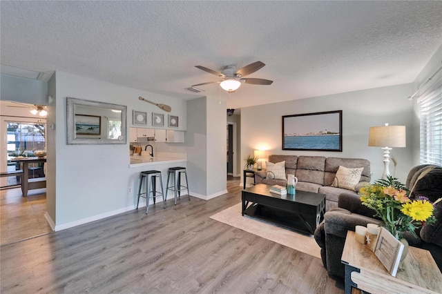 1349 New Bedford Dr Unit 6, Sun City Center, FL 33573 - living area with a ceiling fan, a textured ceiling, wood finished floors, and baseboards