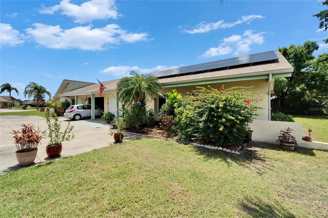1349 New Bedford Dr Unit 6, Sun City Center, FL 33573 - view of front of home featuring concrete driveway, solar panels, a front yard, stucco siding, and an attached garage