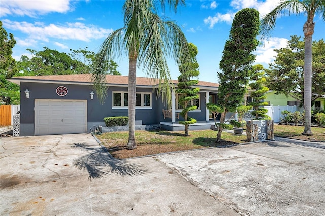 ranch-style home with fence, a garage, driveway, and stucco siding
