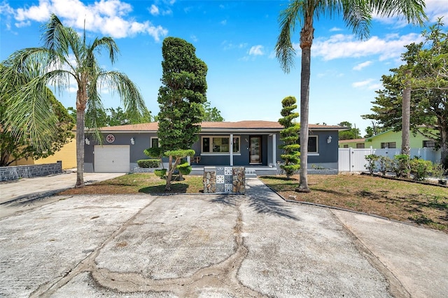 view of front of property featuring a garage, fence, stucco siding, and concrete driveway