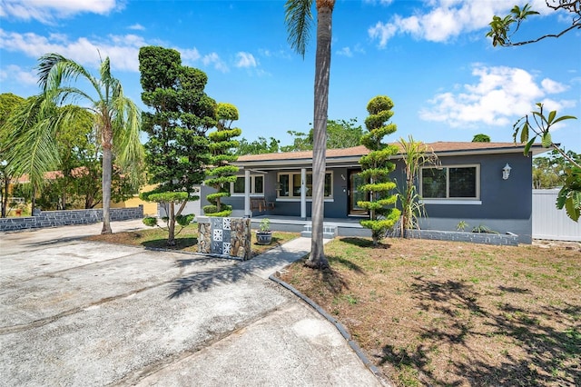 view of front of property with stucco siding, covered porch, and fence