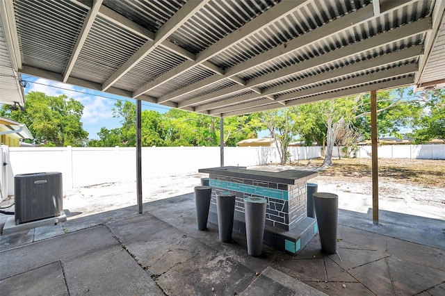view of patio / terrace with central AC unit, a fenced backyard, and outdoor dry bar