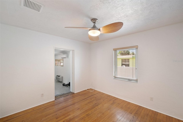 spare room featuring light wood-style floors, baseboards, a ceiling fan, and visible vents