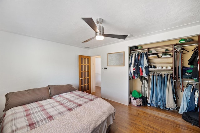 bedroom with a closet, ceiling fan, wood finished floors, and visible vents
