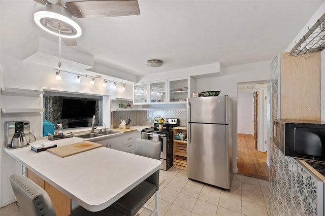kitchen featuring open shelves, a peninsula, rail lighting, a sink, and appliances with stainless steel finishes