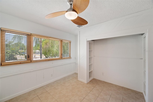 unfurnished bedroom featuring a textured ceiling, multiple windows, light tile patterned floors, and a closet