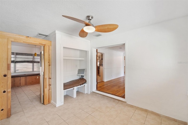 interior space with a closet, a ceiling fan, a textured ceiling, and visible vents