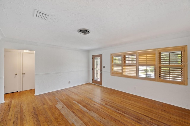 interior space featuring a textured ceiling, visible vents, and light wood finished floors